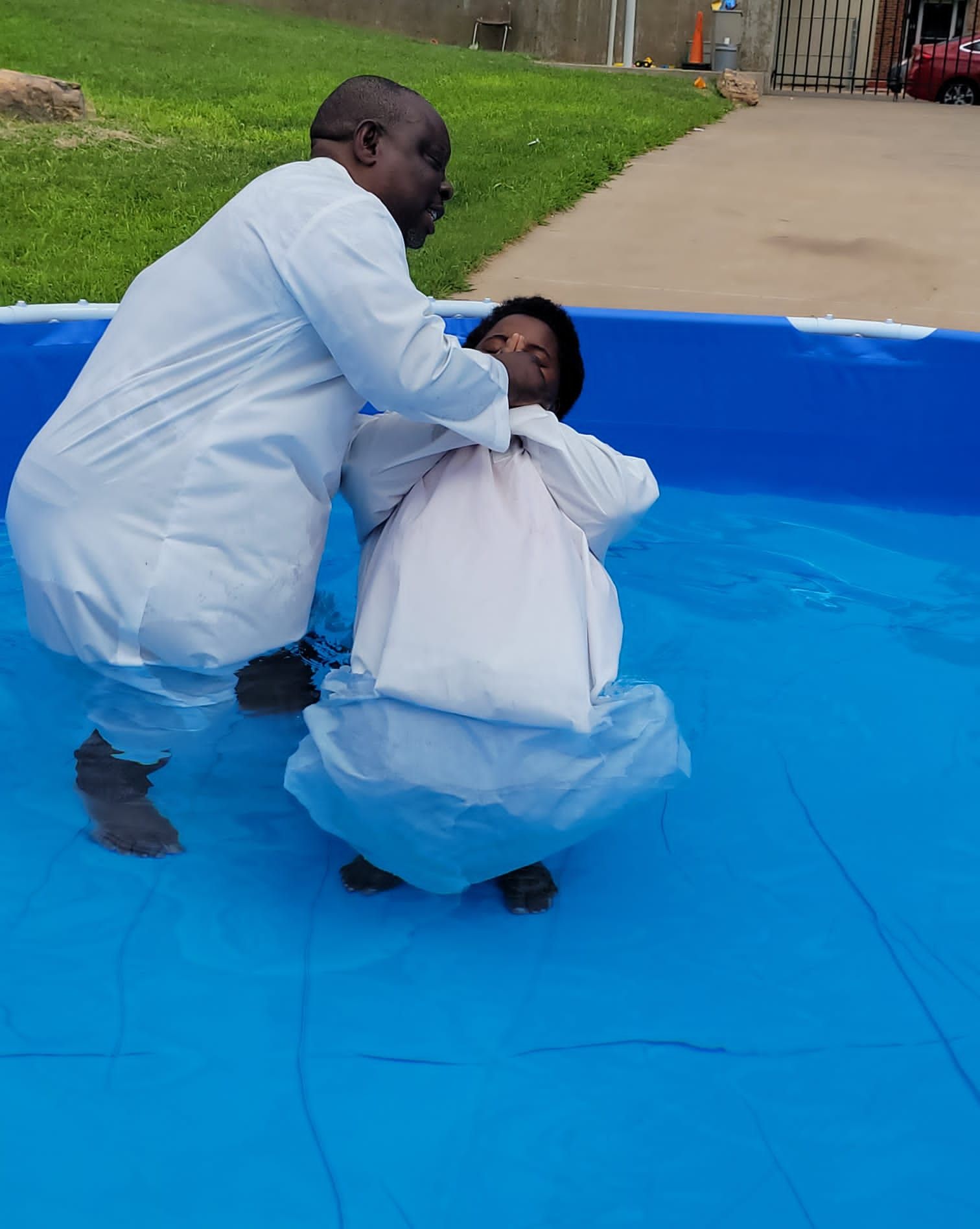 A man is baptizing a woman in a pool.