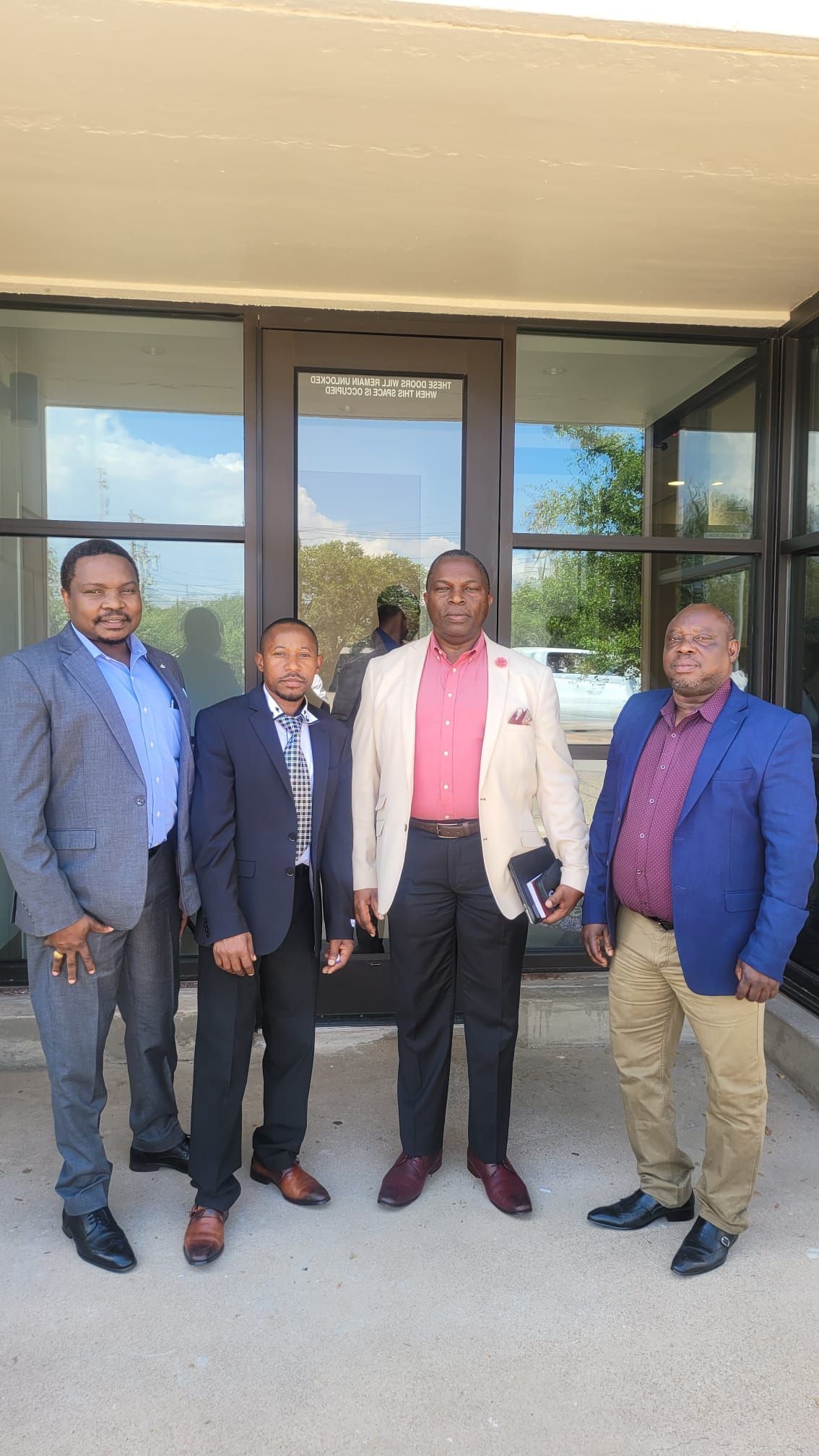 A group of men in suits are standing in front of a building.