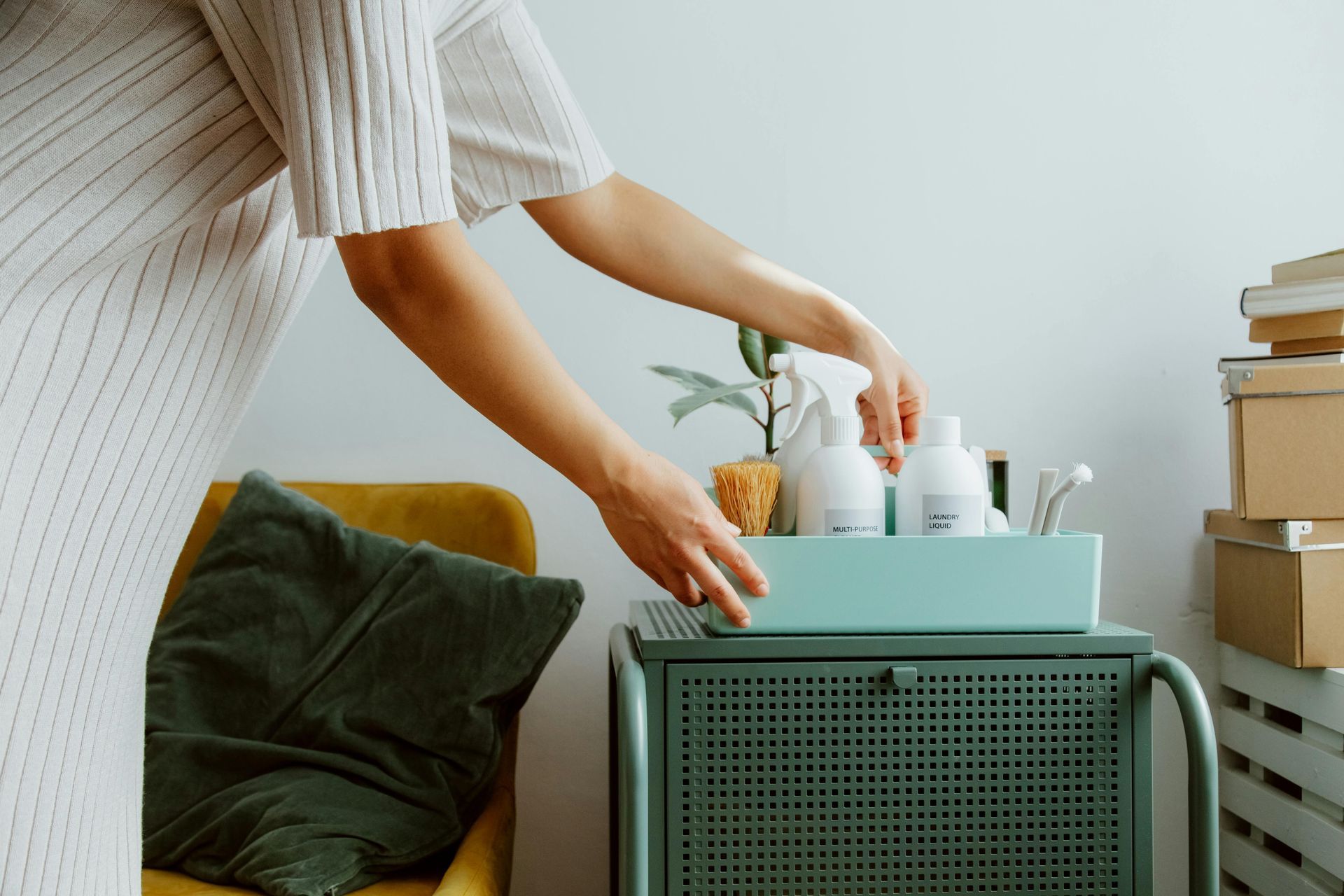A woman is putting cleaning supplies in a tray on a table.