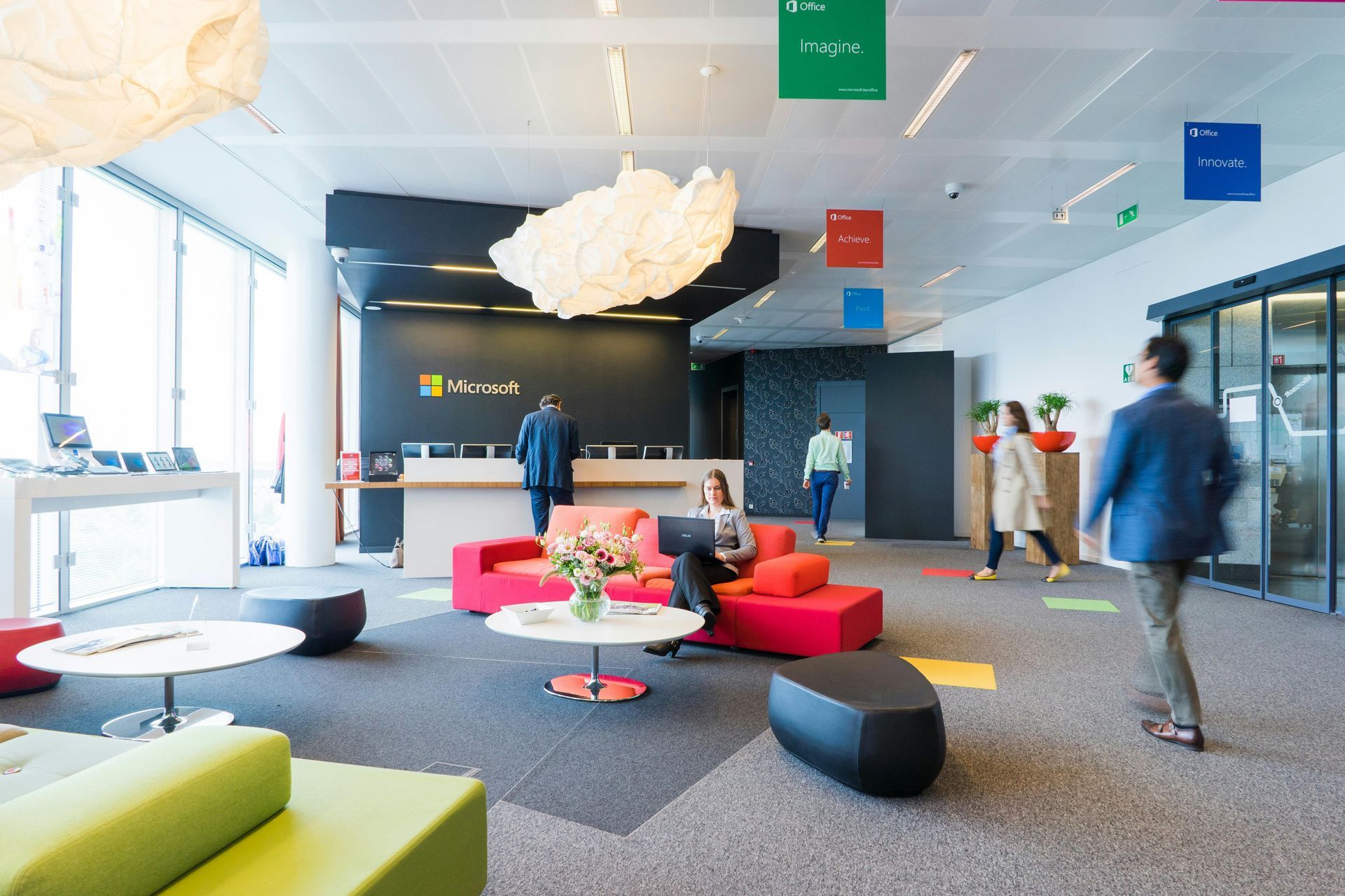 A group of people are walking through a lobby in an office building.