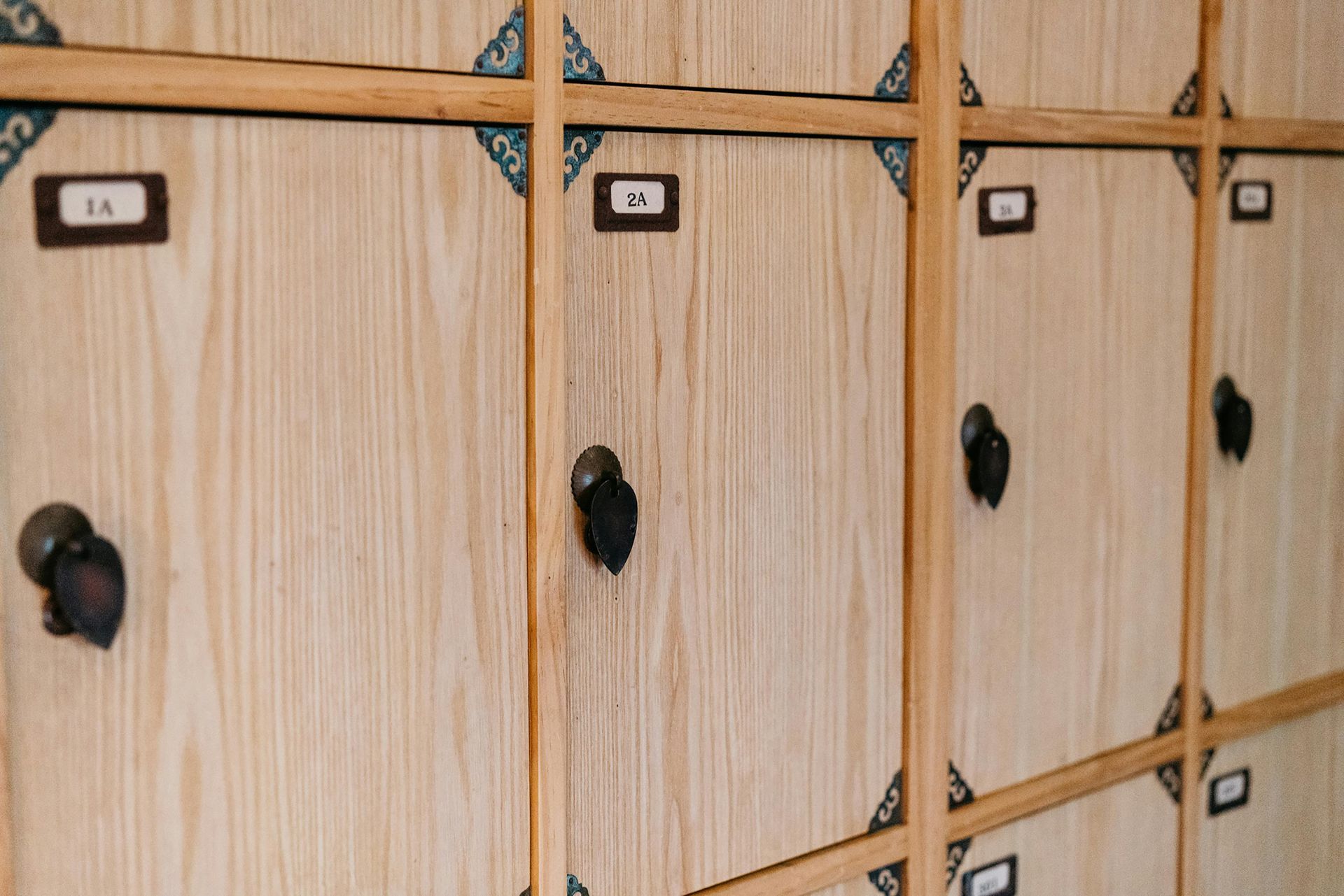 A row of wooden lockers with black handles and numbers on them.