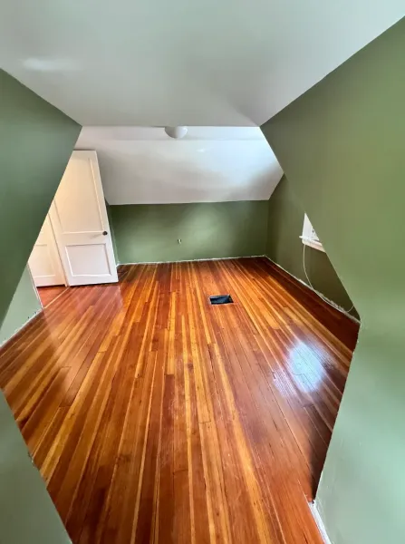 An empty room with wooden floors and green walls.