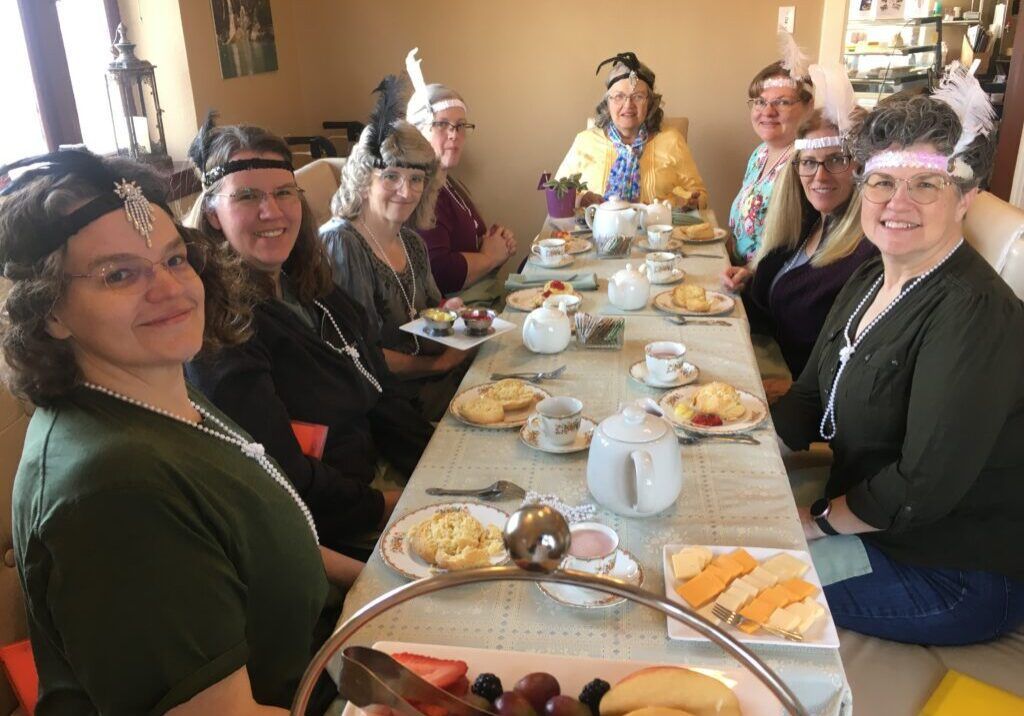 A group of women are sitting at a long table with food.