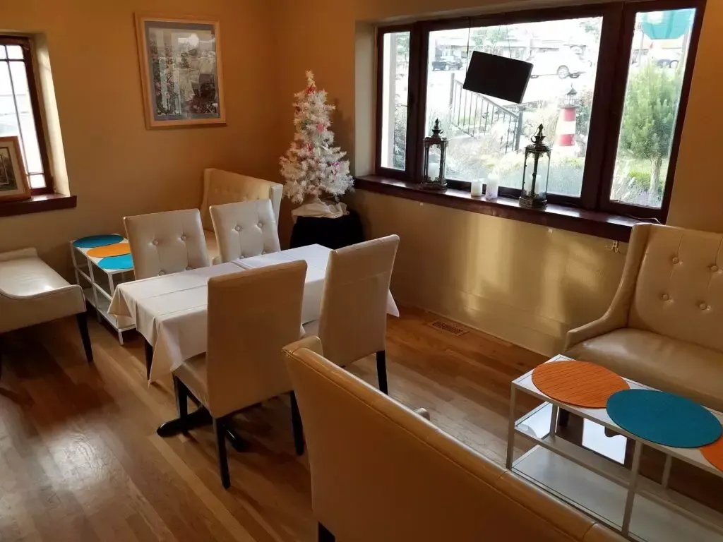 A dining room with a table and chairs and a christmas tree in the window.