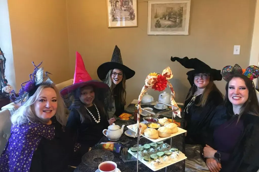 A group of women dressed as witches are sitting around a table.