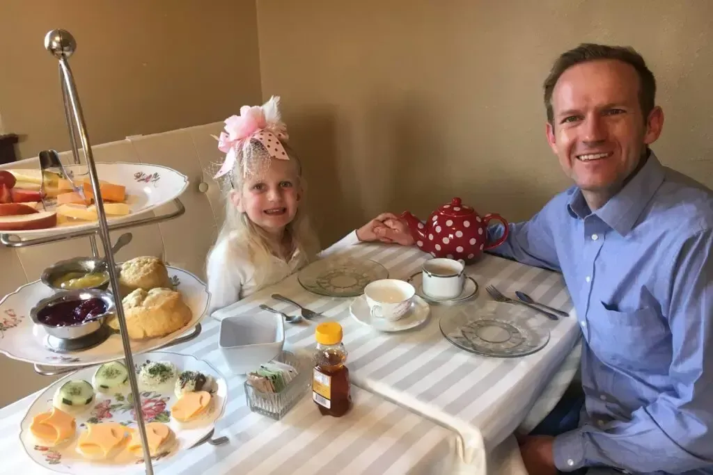 A man and a little girl are sitting at a table with food.