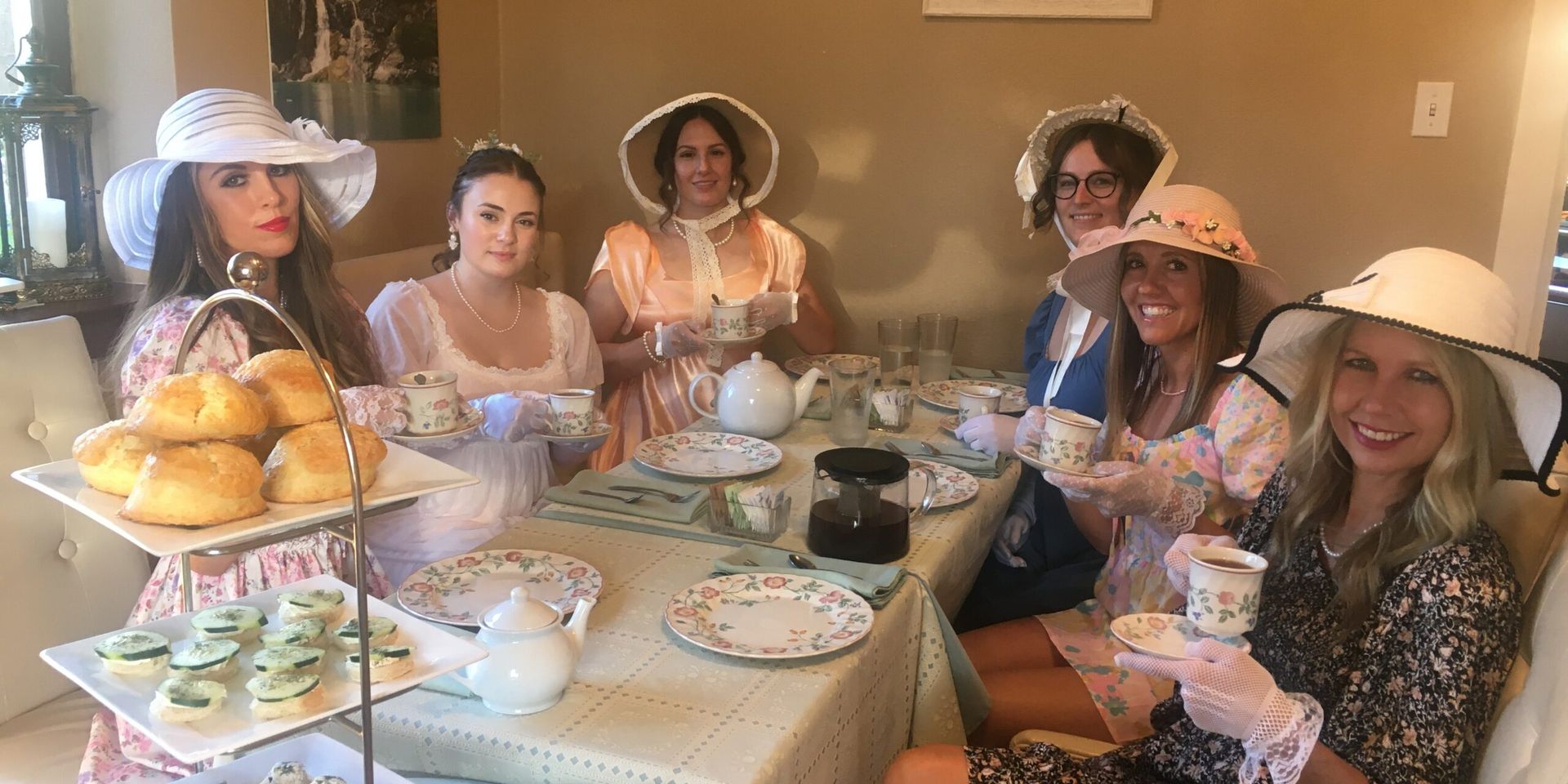 A group of women are sitting at a table drinking tea.