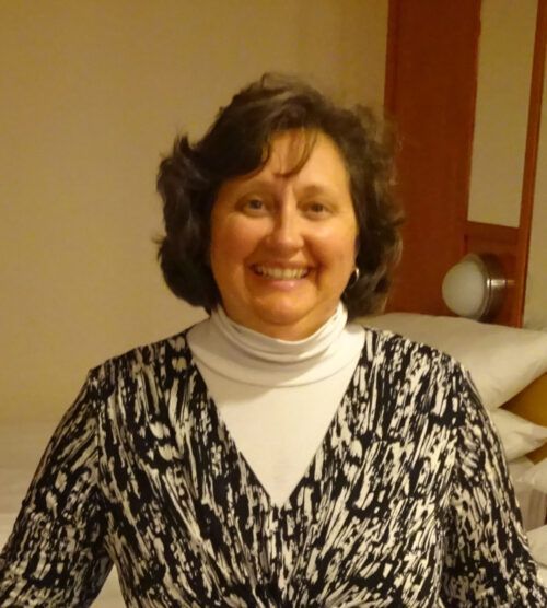 A woman in a black and white sweater smiles for the camera