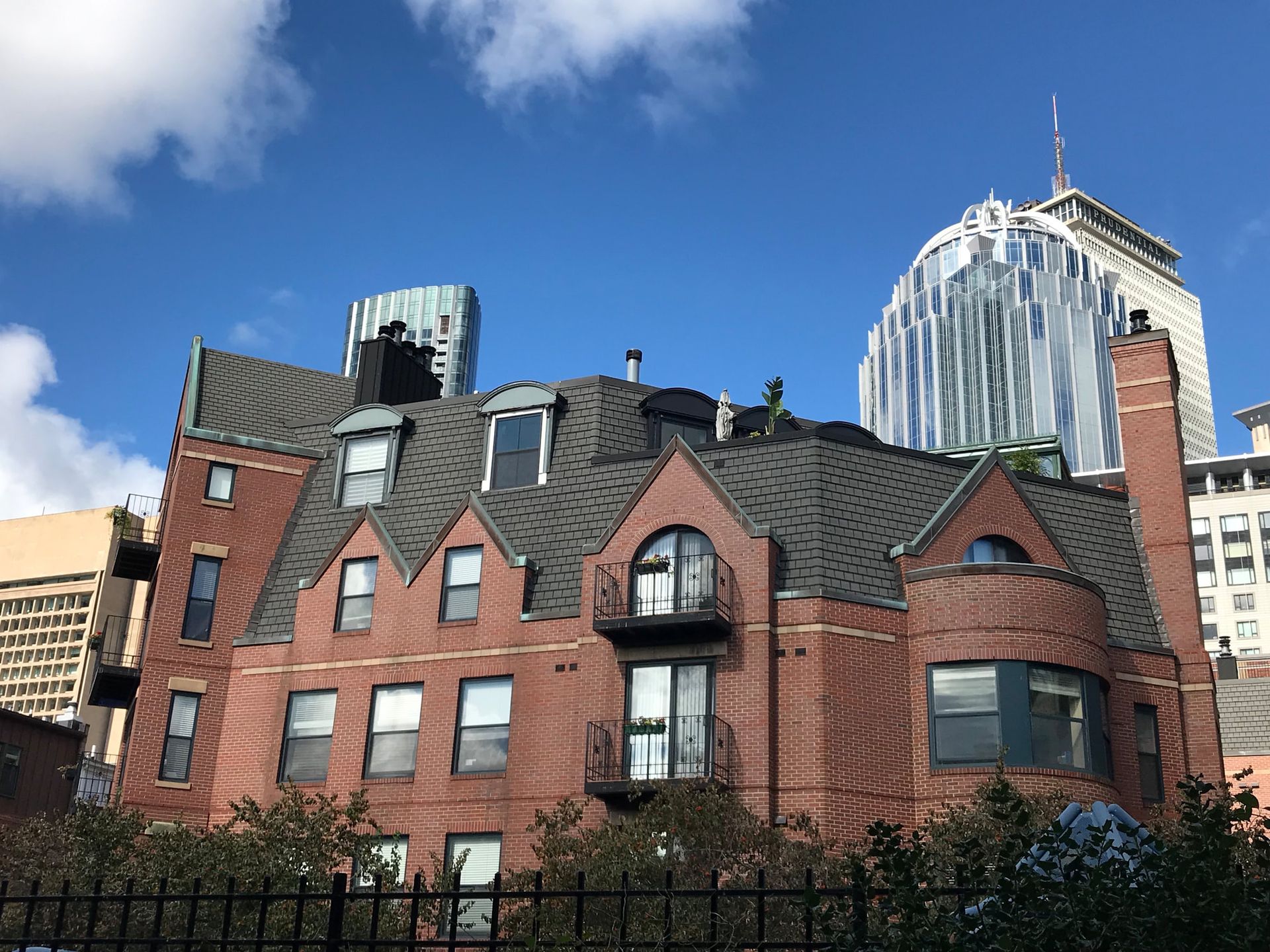 A large brick building with a gray roof and a fence in front of it.