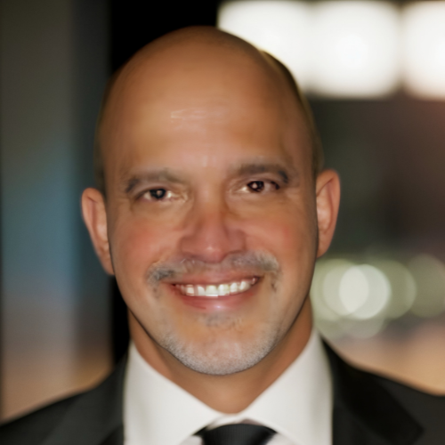 A bald man in a suit and tie smiles for the camera