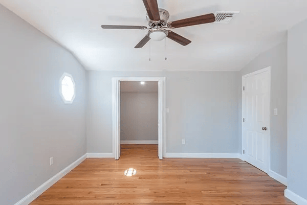 An empty room with hardwood floors and a ceiling fan