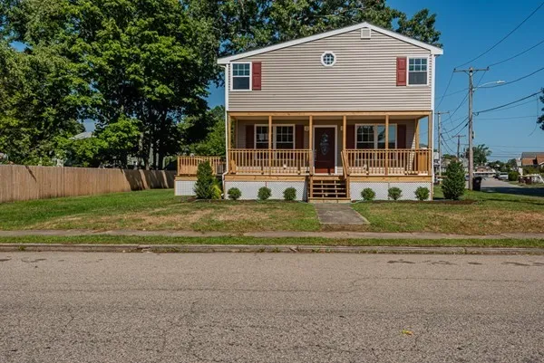 A large house with a large porch is sitting on the side of the road.