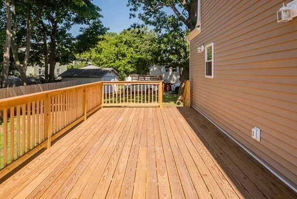 A large wooden deck with a railing in front of a house