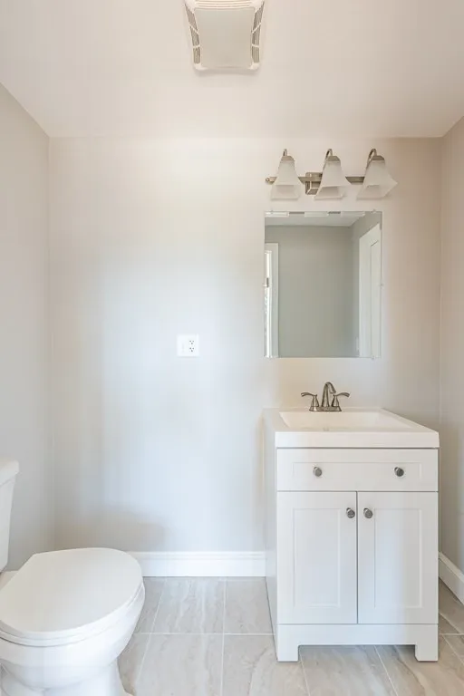 A bathroom with a toilet , sink and mirror.
