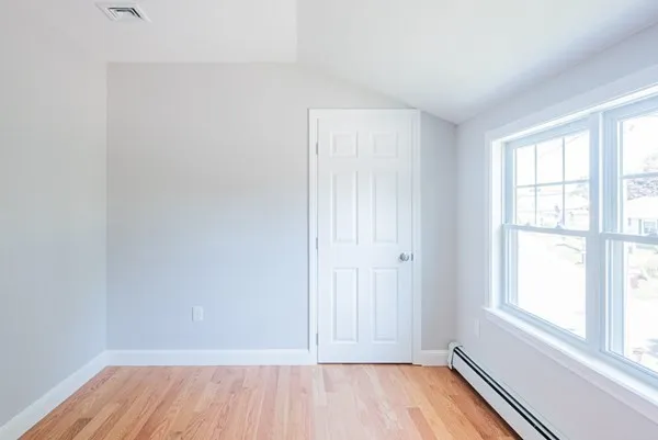 An empty room with hardwood floors and white walls.