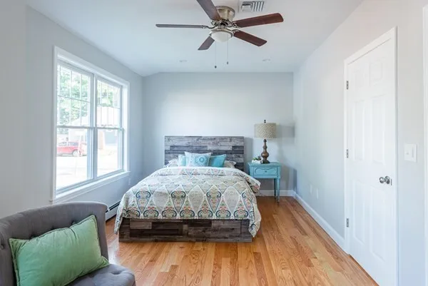 A bedroom with a bed , chair and ceiling fan.