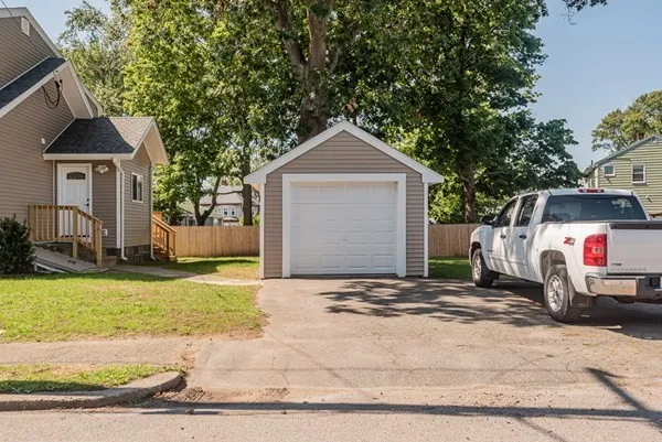 A white truck is parked in front of a garage next to a house.