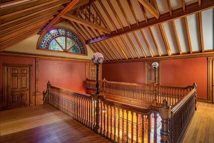 An empty room with a wooden railing and a stained glass window.
