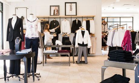 A woman is standing in a clothing store looking at clothes on display.