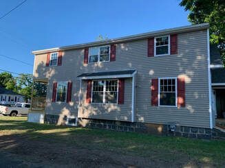 A large house with red shutters and a truck parked in front of it.
