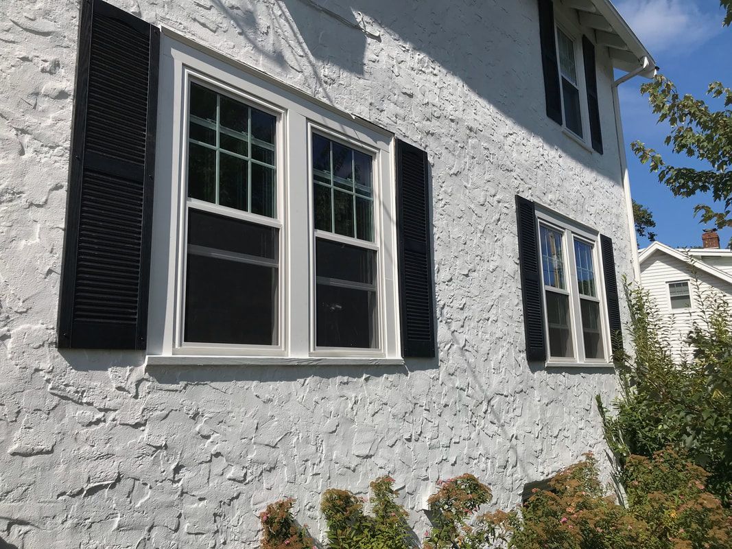 A white house with black shutters on the windows.