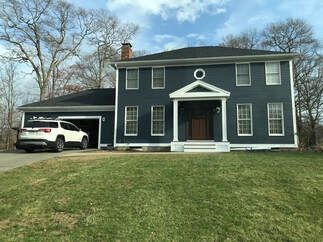 A large blue house with a white suv parked in front of it.