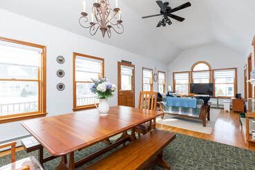 A living room with a wooden table and benches and a ceiling fan.