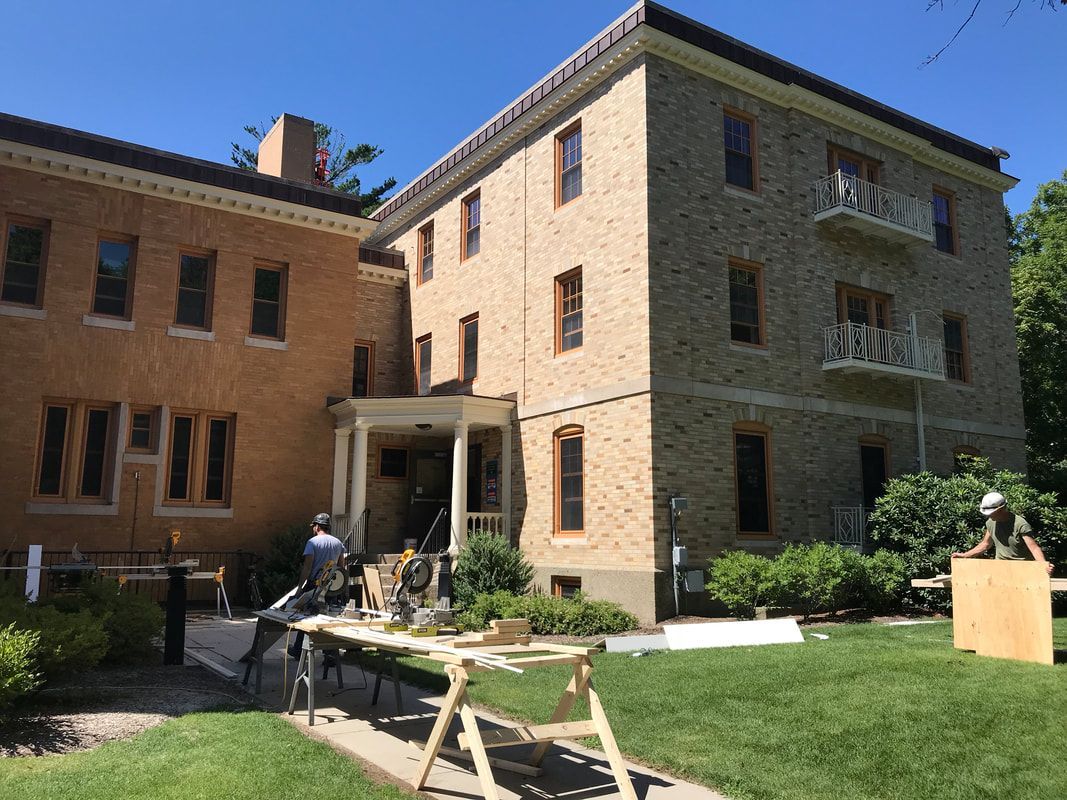 A large brick building with a wooden table in front of it.