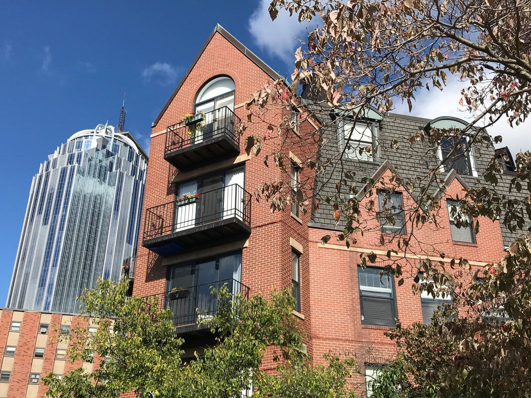 A brick building with a balcony and a skyscraper in the background.
