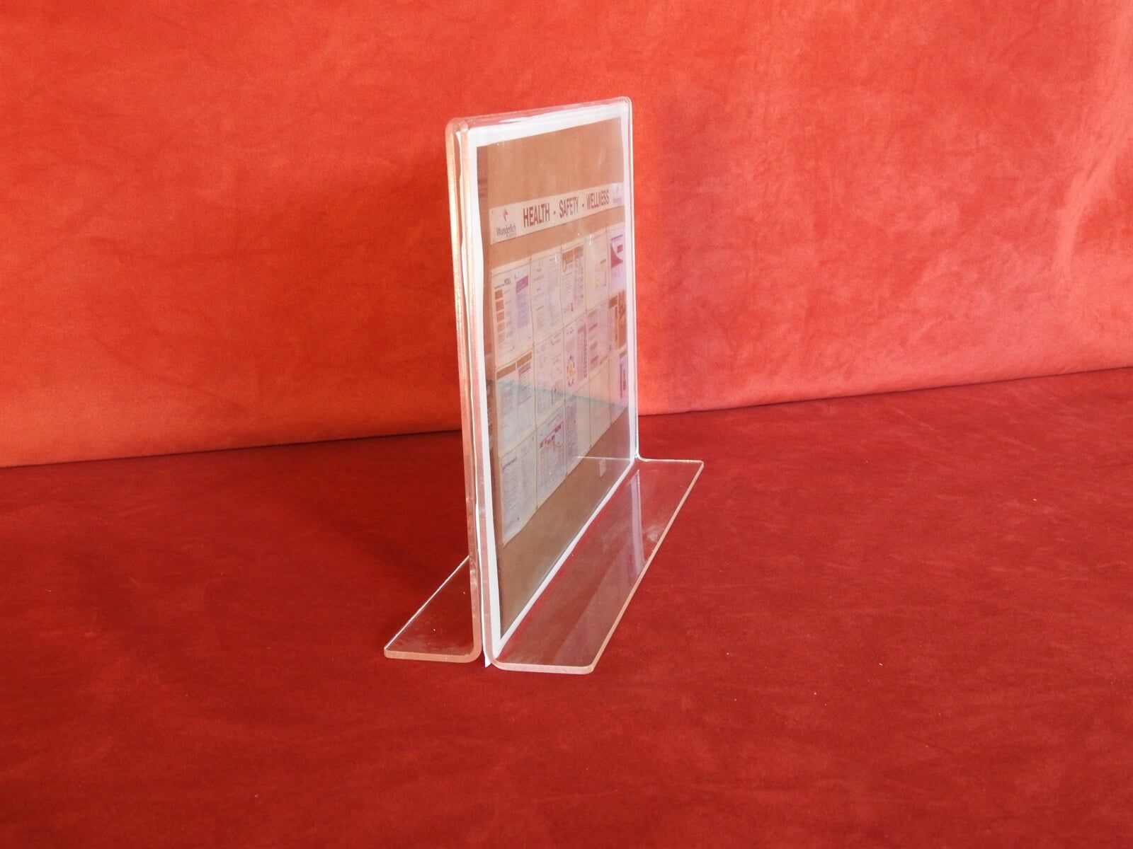A Clear Acrylic Sign Holder Is Sitting On A Red Couch — Light Industries in Bowral, NSW