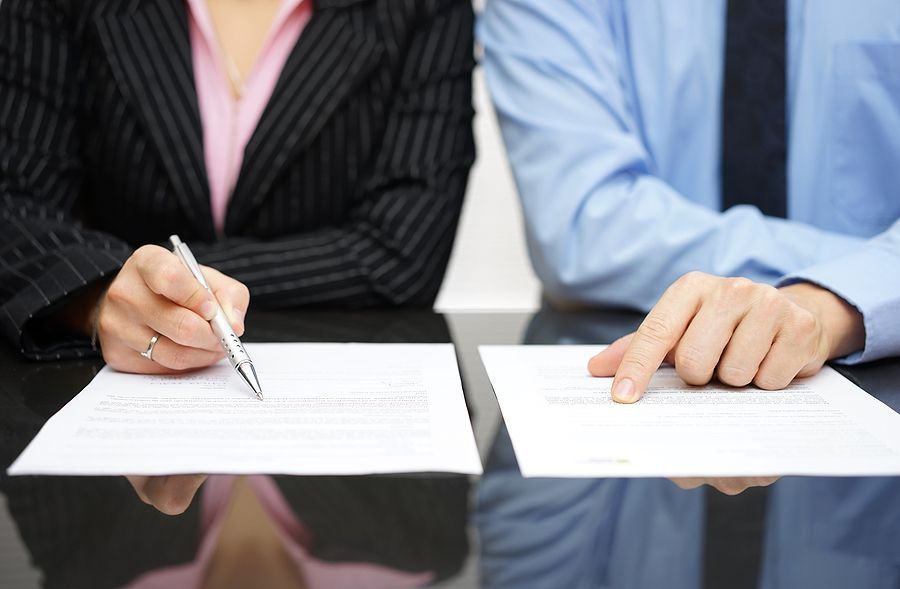 A man and a woman are sitting at a table signing papers.