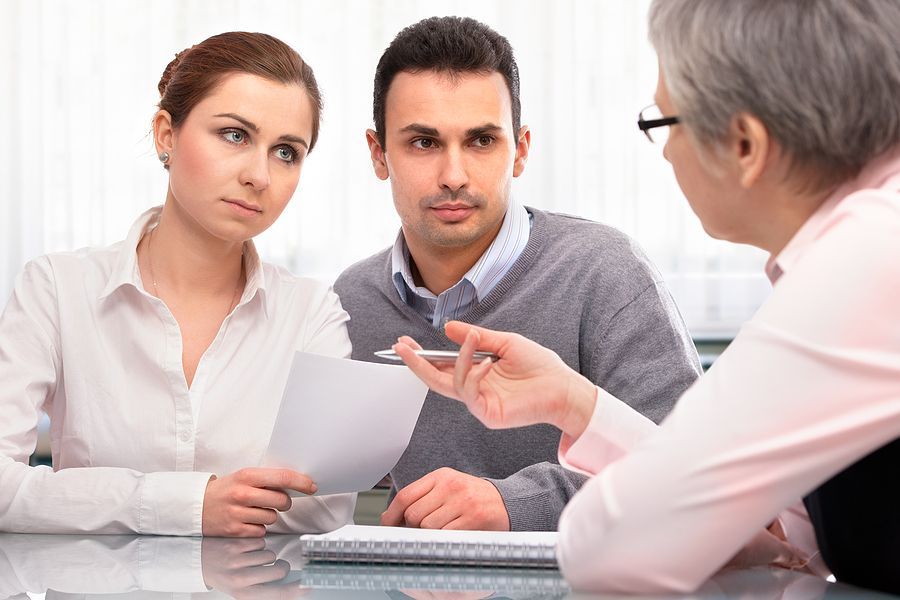 A man and a woman are sitting at a table talking to a woman.