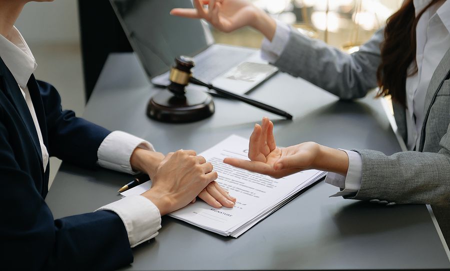 A woman is giving a document to another woman at a table.