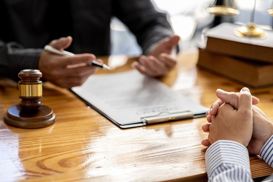A man is sitting at a wooden table talking to a lawyer.