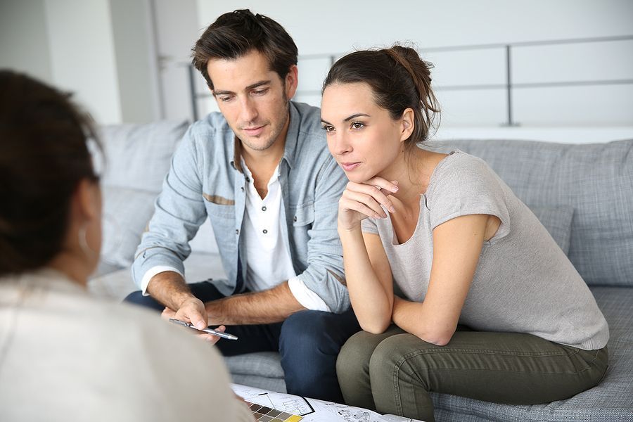 A man and a woman are sitting on a couch talking to a woman.