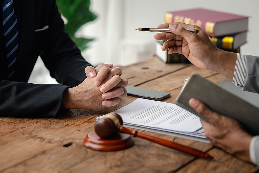 A man is holding a pen while sitting at a table with a judge 's gavel.