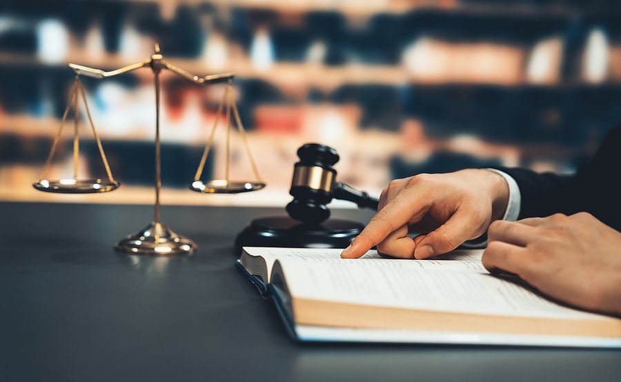 A judge is reading a book in front of a gavel and scales of justice.