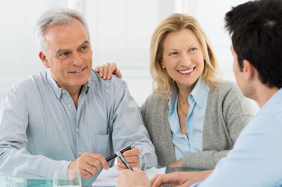 An older couple is sitting at a table talking to a man.