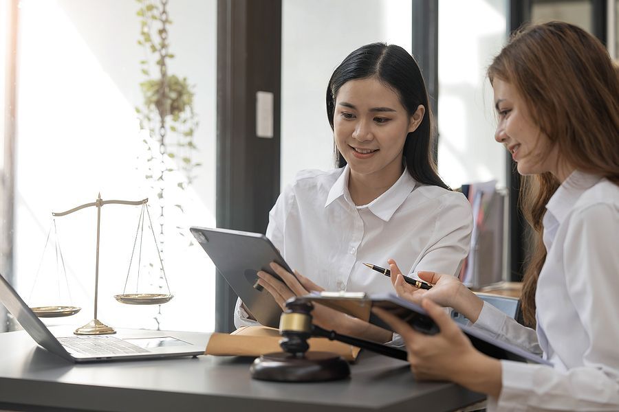 Two women are sitting at a table looking at a tablet.