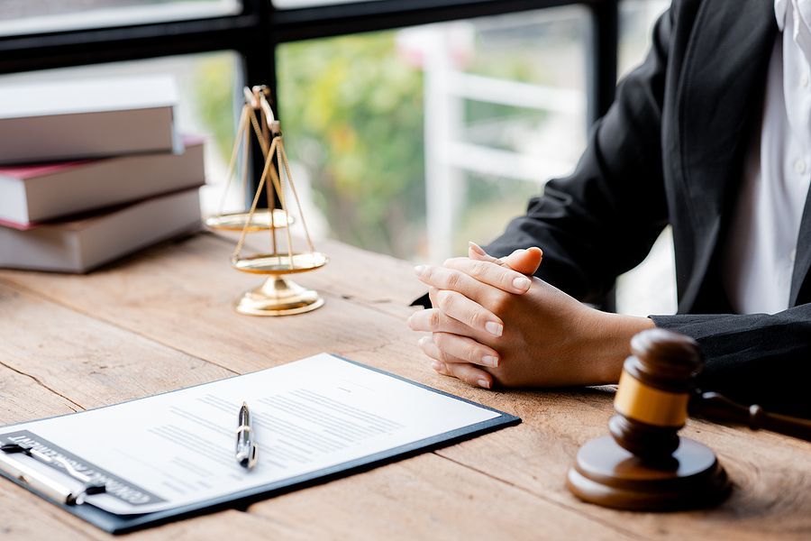 A judge is sitting at a wooden table with a gavel and scales of justice.