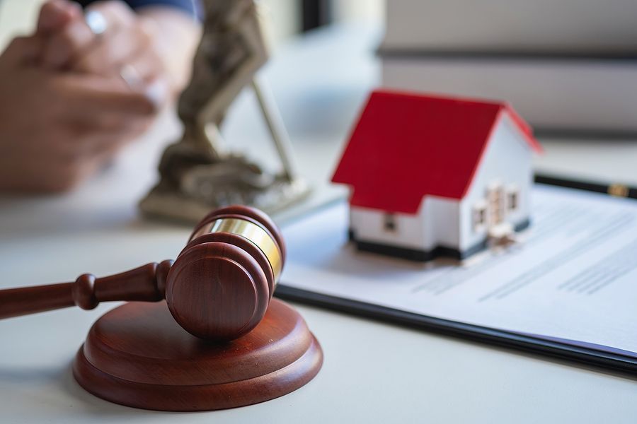 A judge 's gavel is sitting on top of a clipboard next to a model house.
