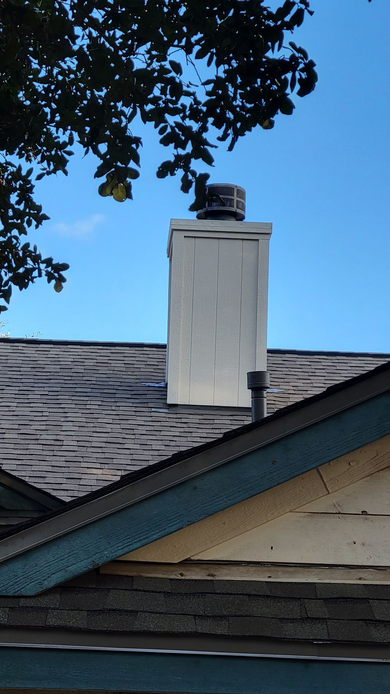 A white chimney is on the roof of a house