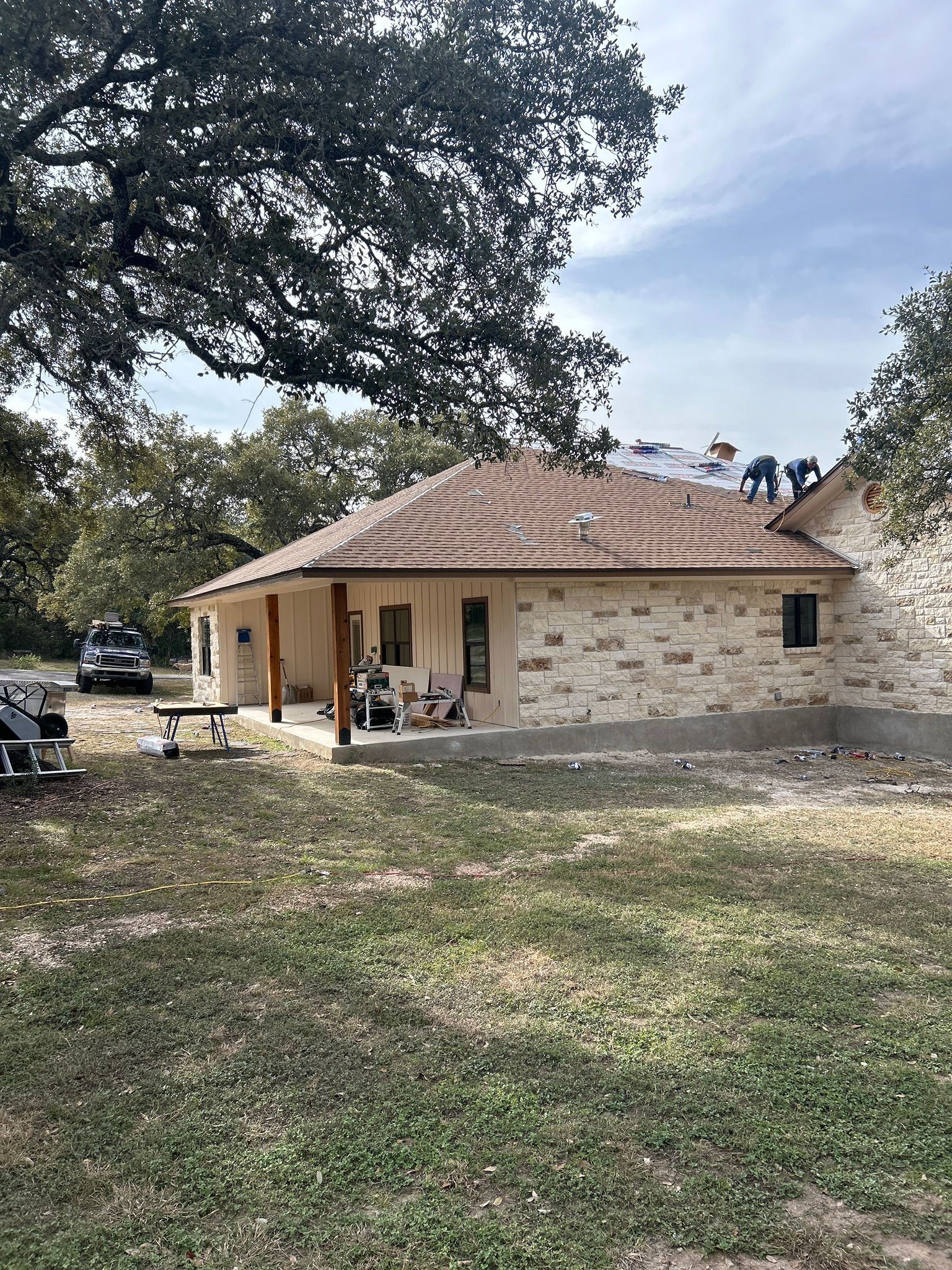 A brick house with a tile roof is sitting on top of a lush green field.