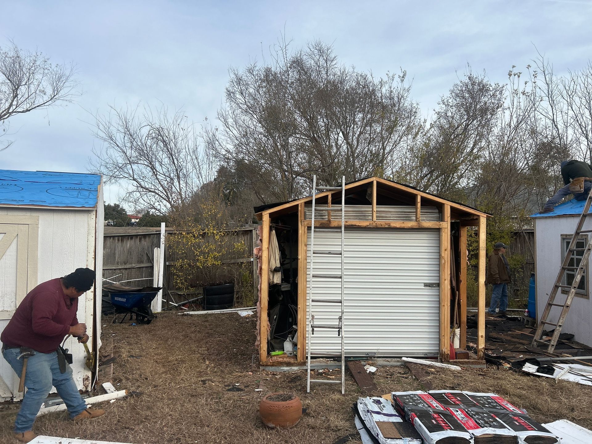 Two men are working on a shed in a backyard.