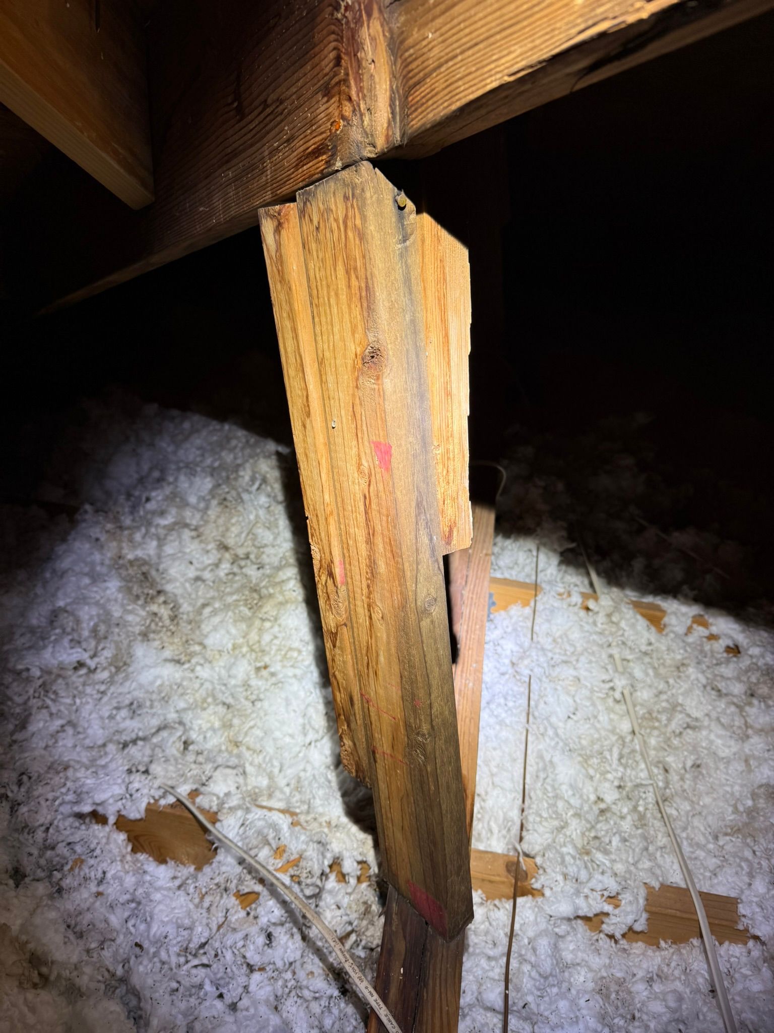 A close up of a wooden post in an attic.