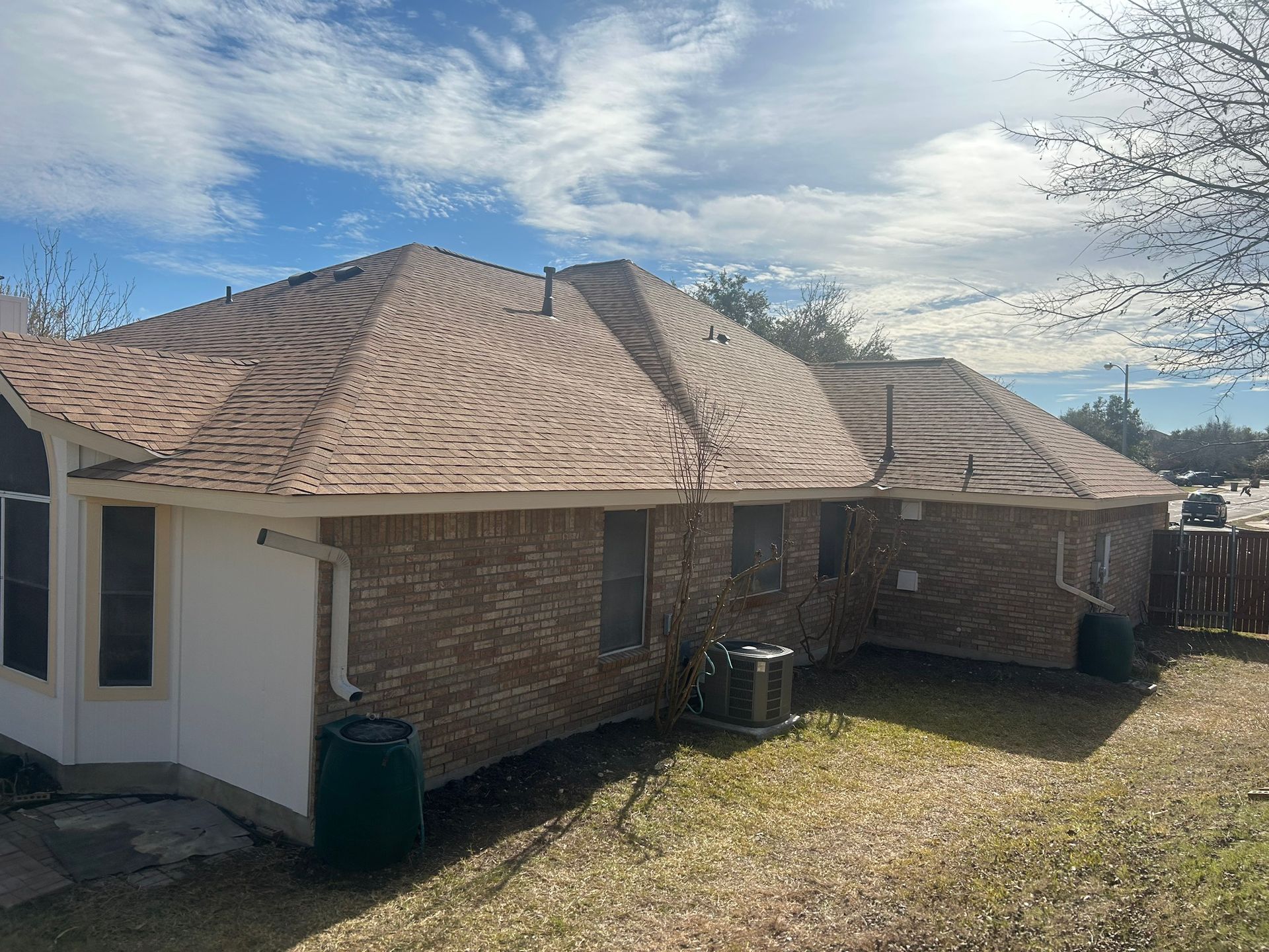 The back of a brick house with a new roof.