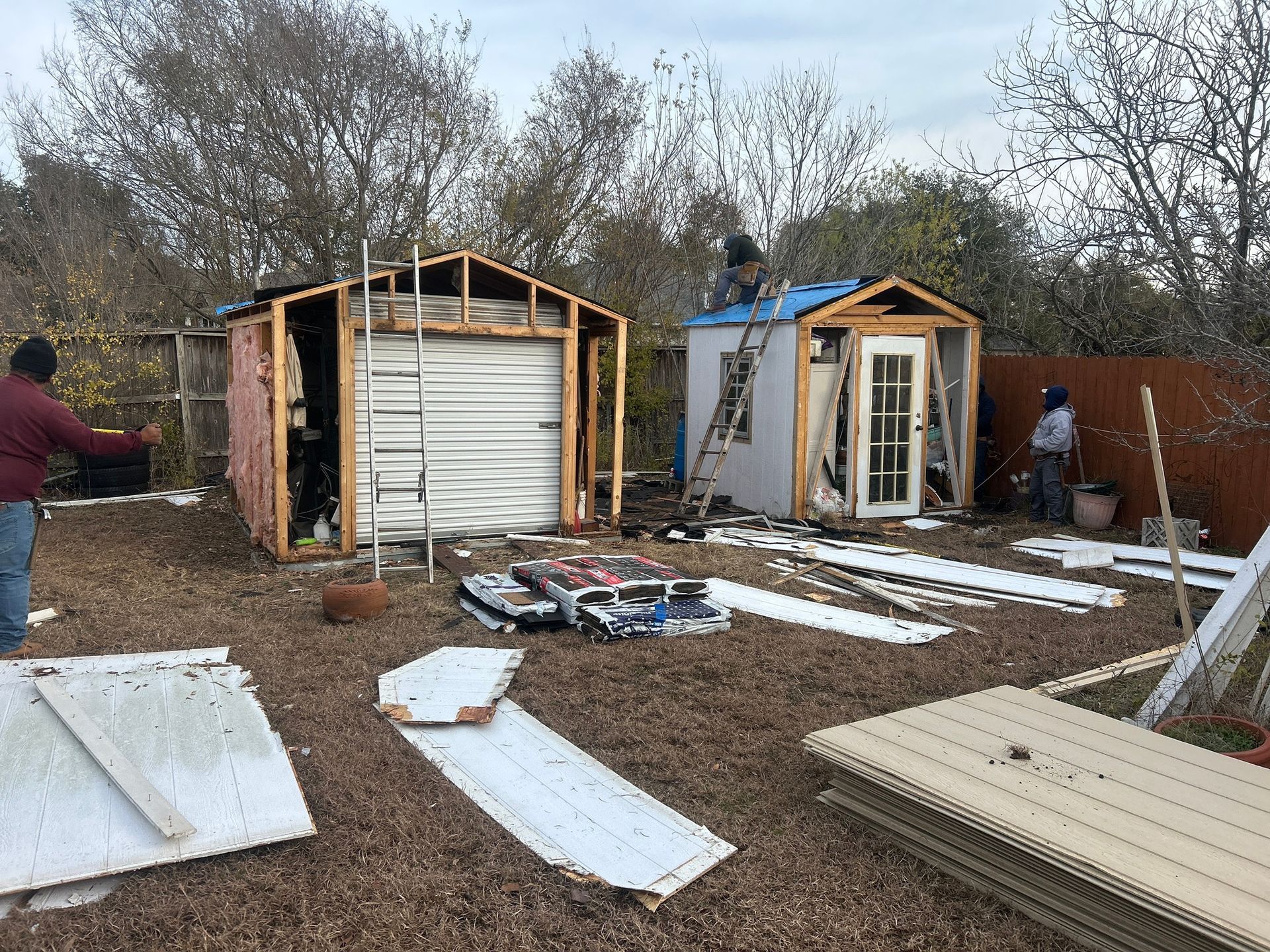 A group of people are working on a shed in a backyard.