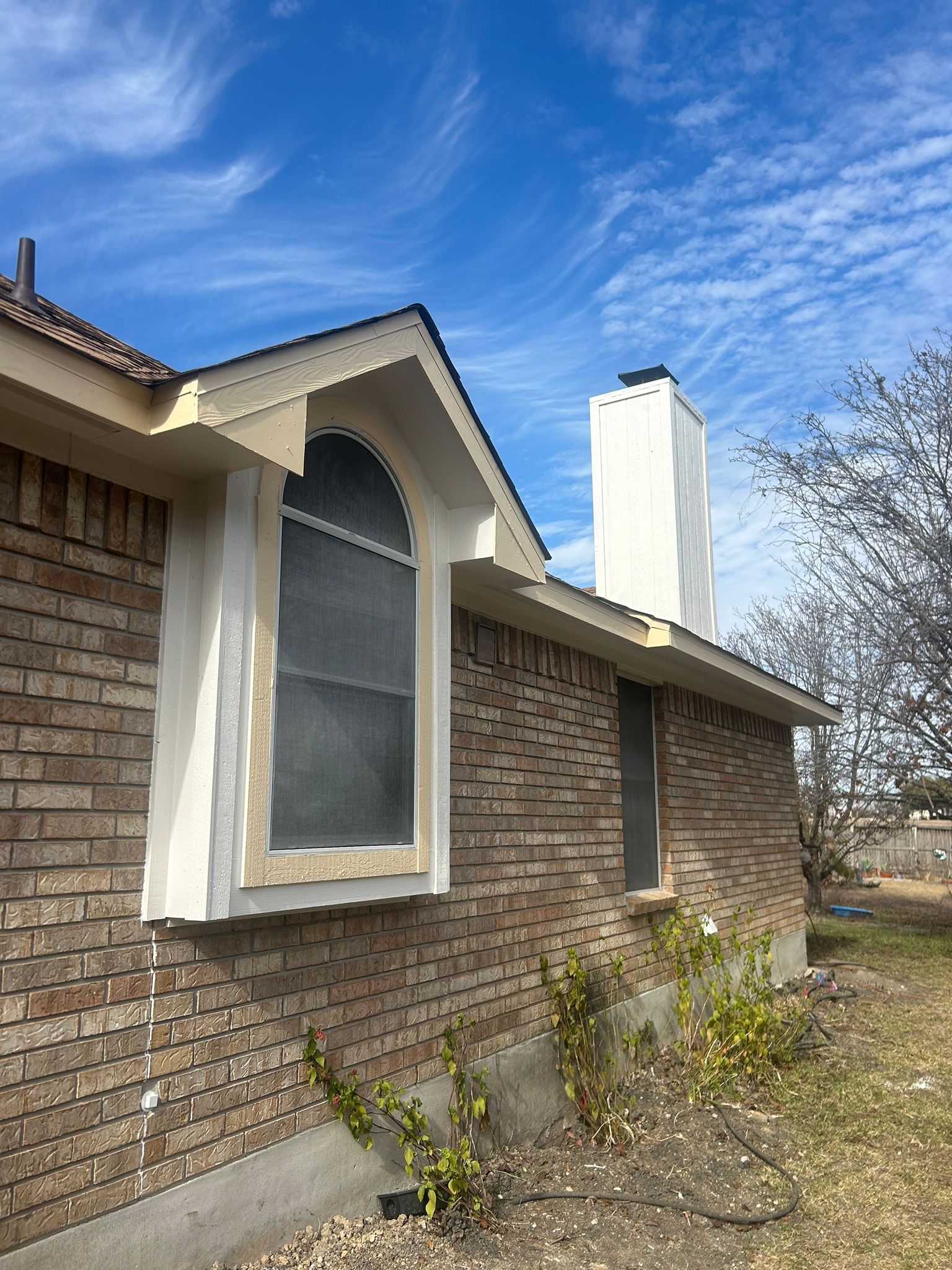 A brick house with a large window and a chimney