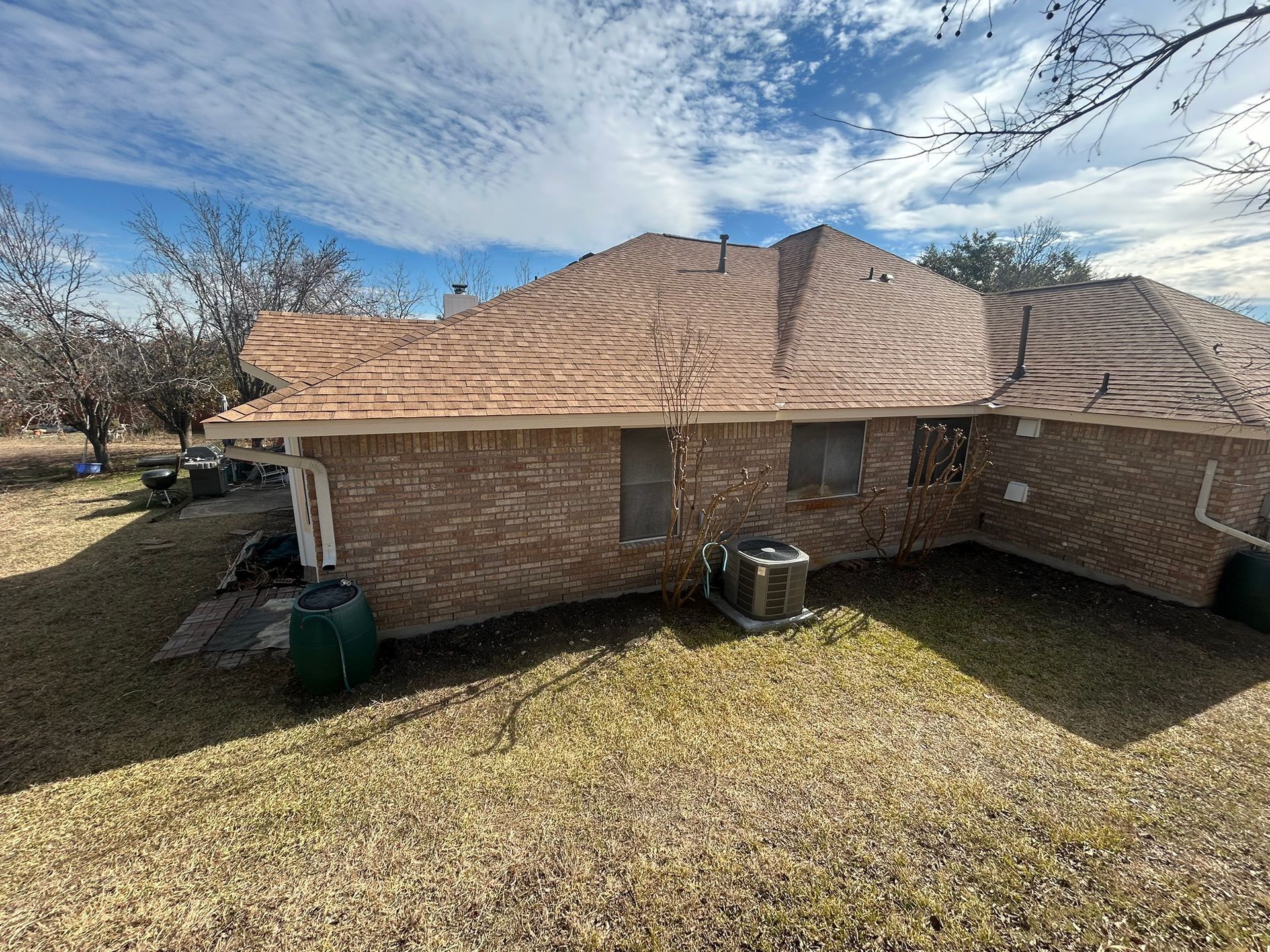 The back of a brick house with a roof that is covered in shingles.