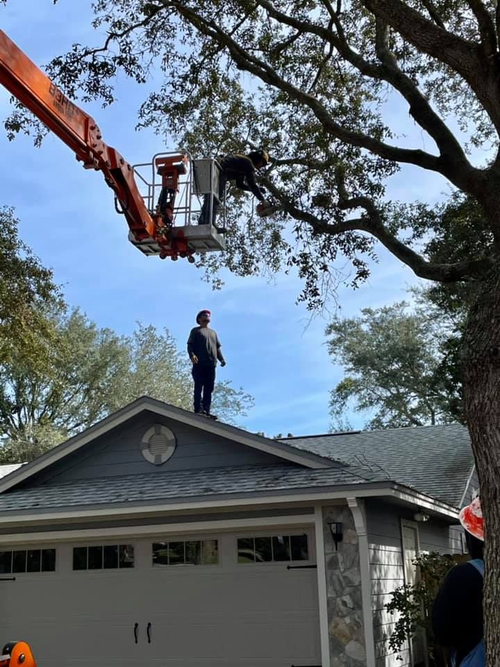 A man is standing on the roof of a house next to a crane.